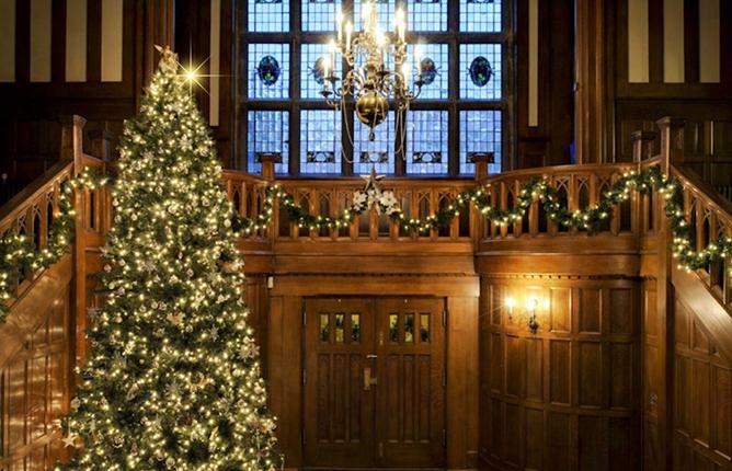 A Christmas tree lit up and glowing in the main foyer of Hatley Castle at Royal Roads University